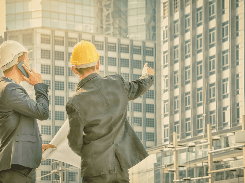 NDT Consultancy - man in a yellow hard hat pointing to a building.